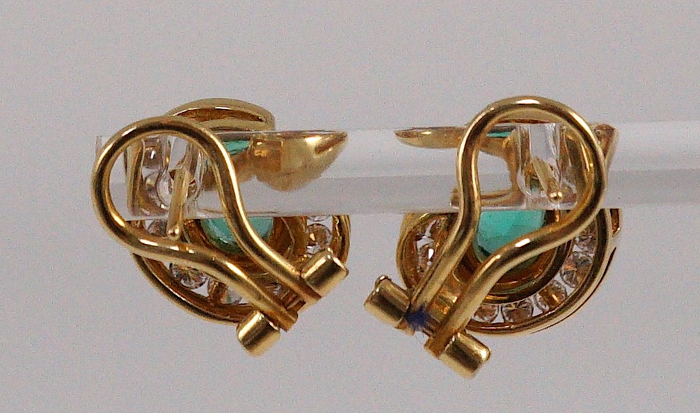 A modern pair of gold (tests as 18ct), emerald and diamond set scrolling cluster earrings